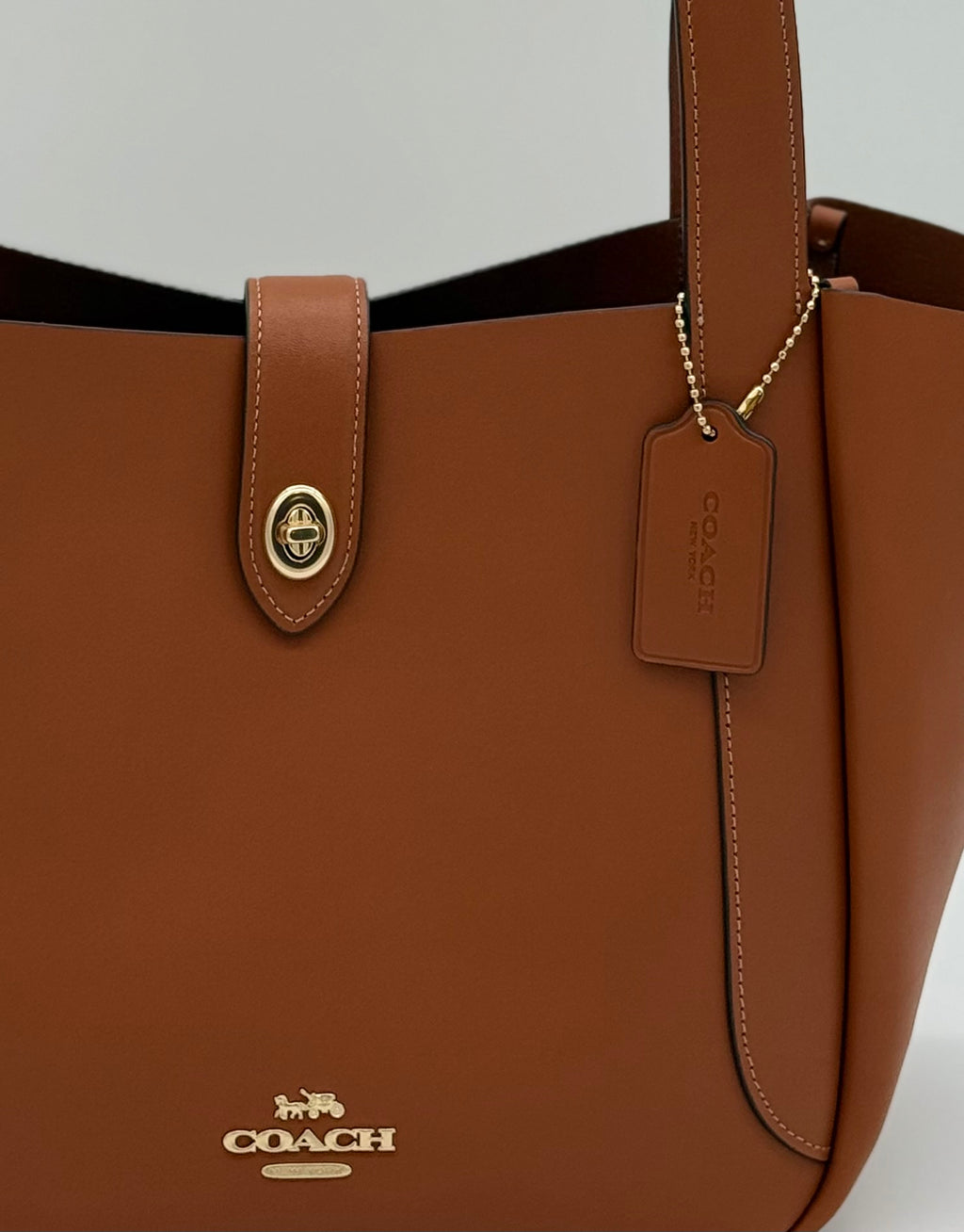 Wunderschöne Coach Tote Bag aus glattem Leder in Gold und Braun, von vorne Nahaufnahme vom Logo und Verschluss