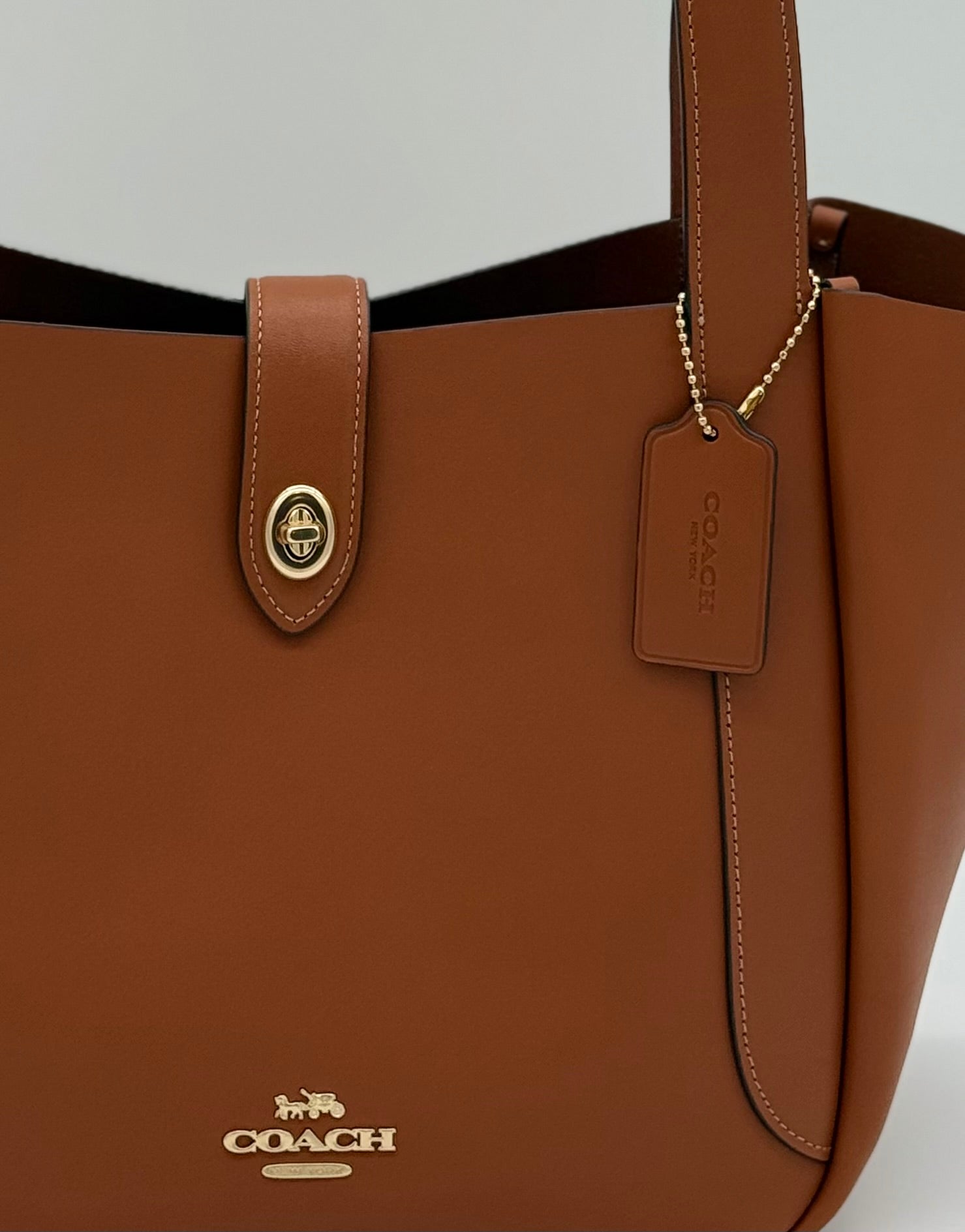Wunderschöne Coach Tote Bag aus glattem Leder in Gold und Braun, von vorne Nahaufnahme vom Logo und Verschluss