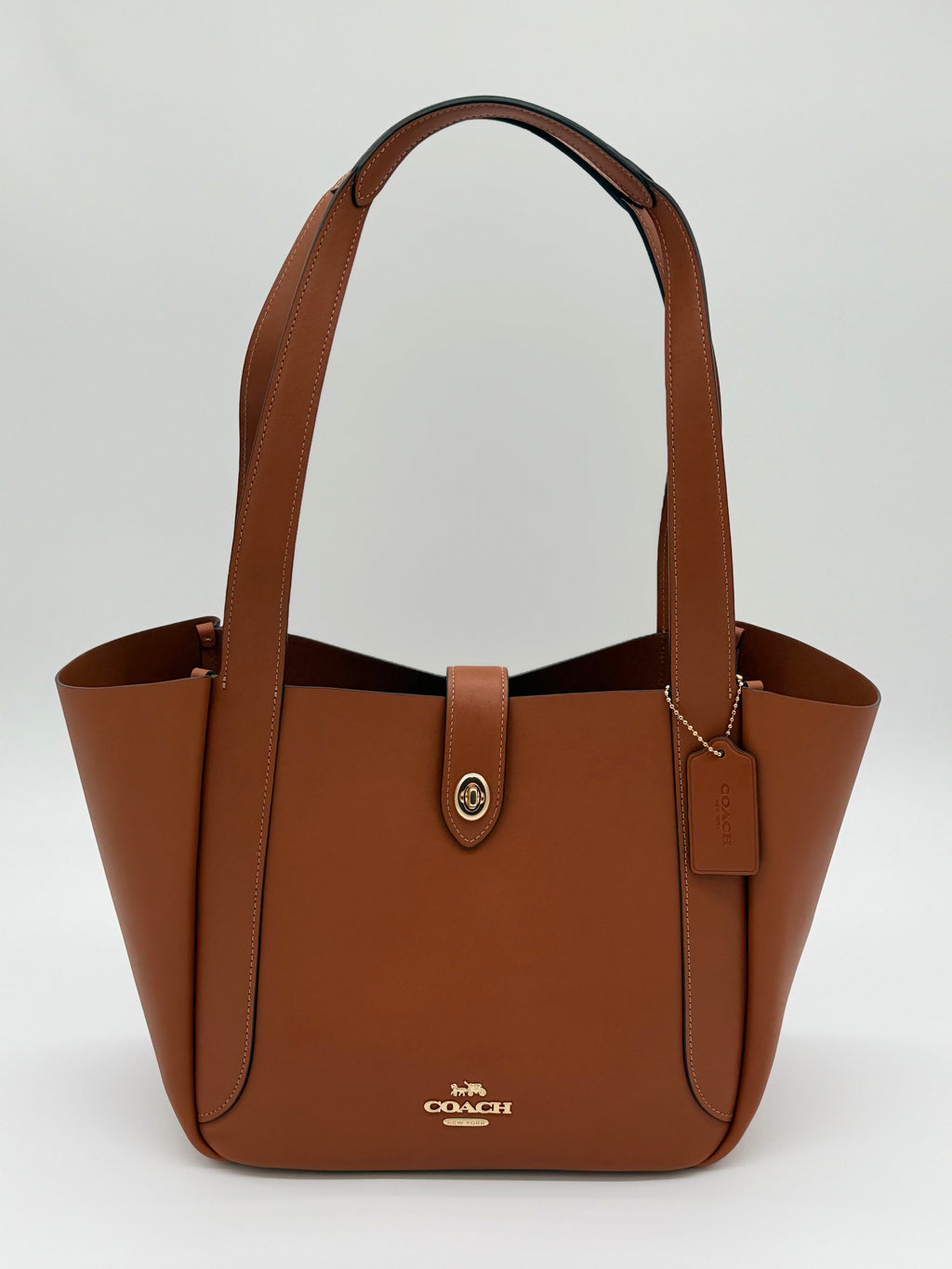 Elegante Coach Tote Bag aus glattem Leder mit praktischem Drehverschluss in Gold und Braun, von vorne