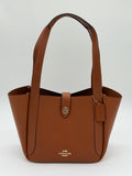 Elegante Coach Tote Bag aus glattem Leder mit praktischem Drehverschluss in Gold und Braun, von vorne
