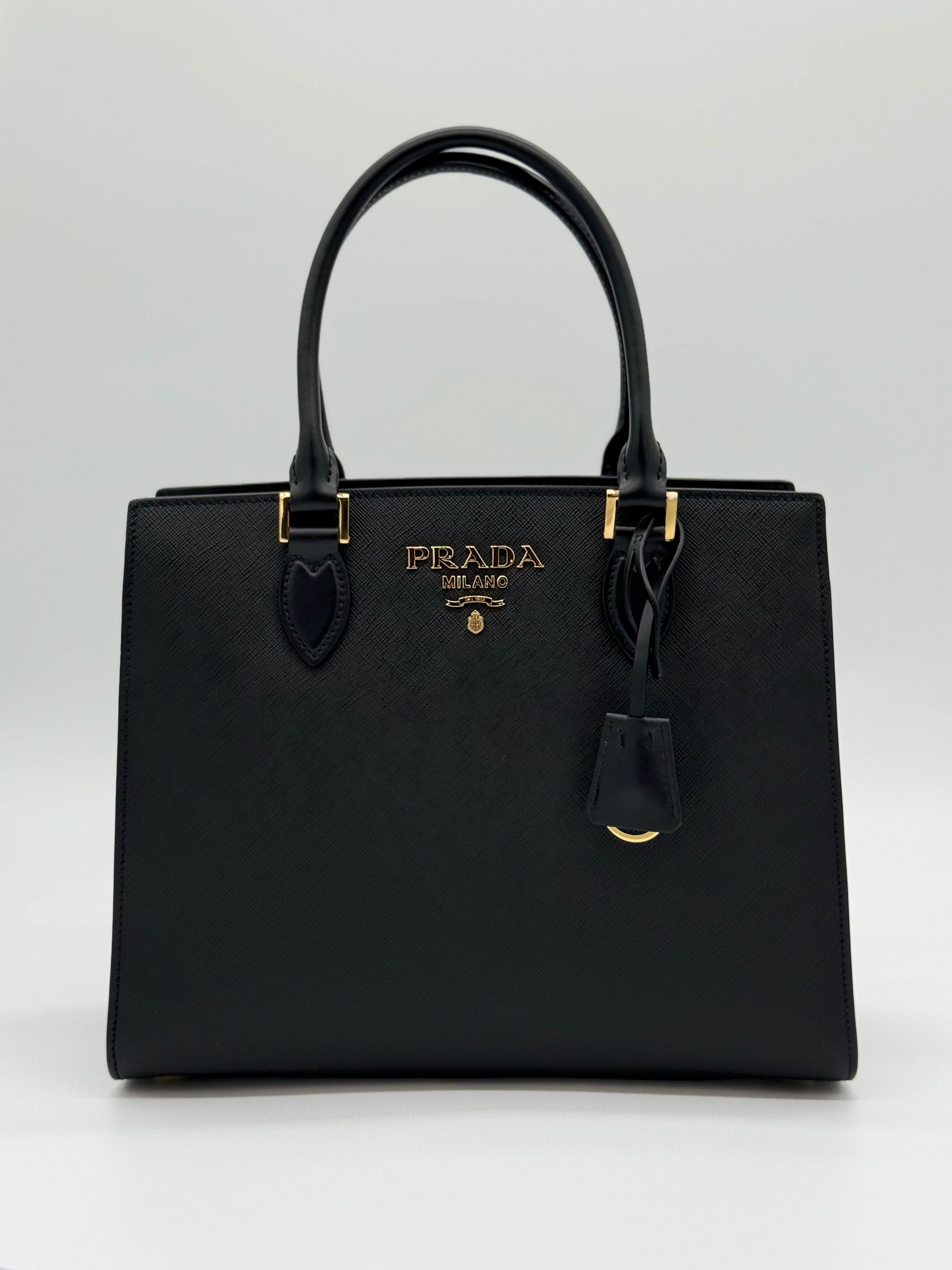 Vorderansicht – „Prada Saffiano Lux Tote Vorderansicht – schwarze Handtasche mit goldenem Prada-Logo
