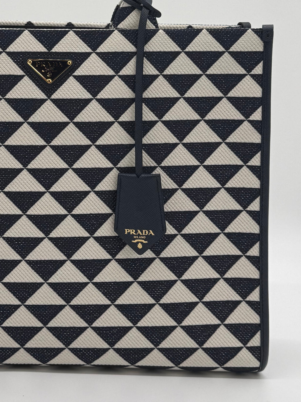 Nahaufnahme des Prada Logos und des Lederanhängers auf dem Jacquard-Stoff.