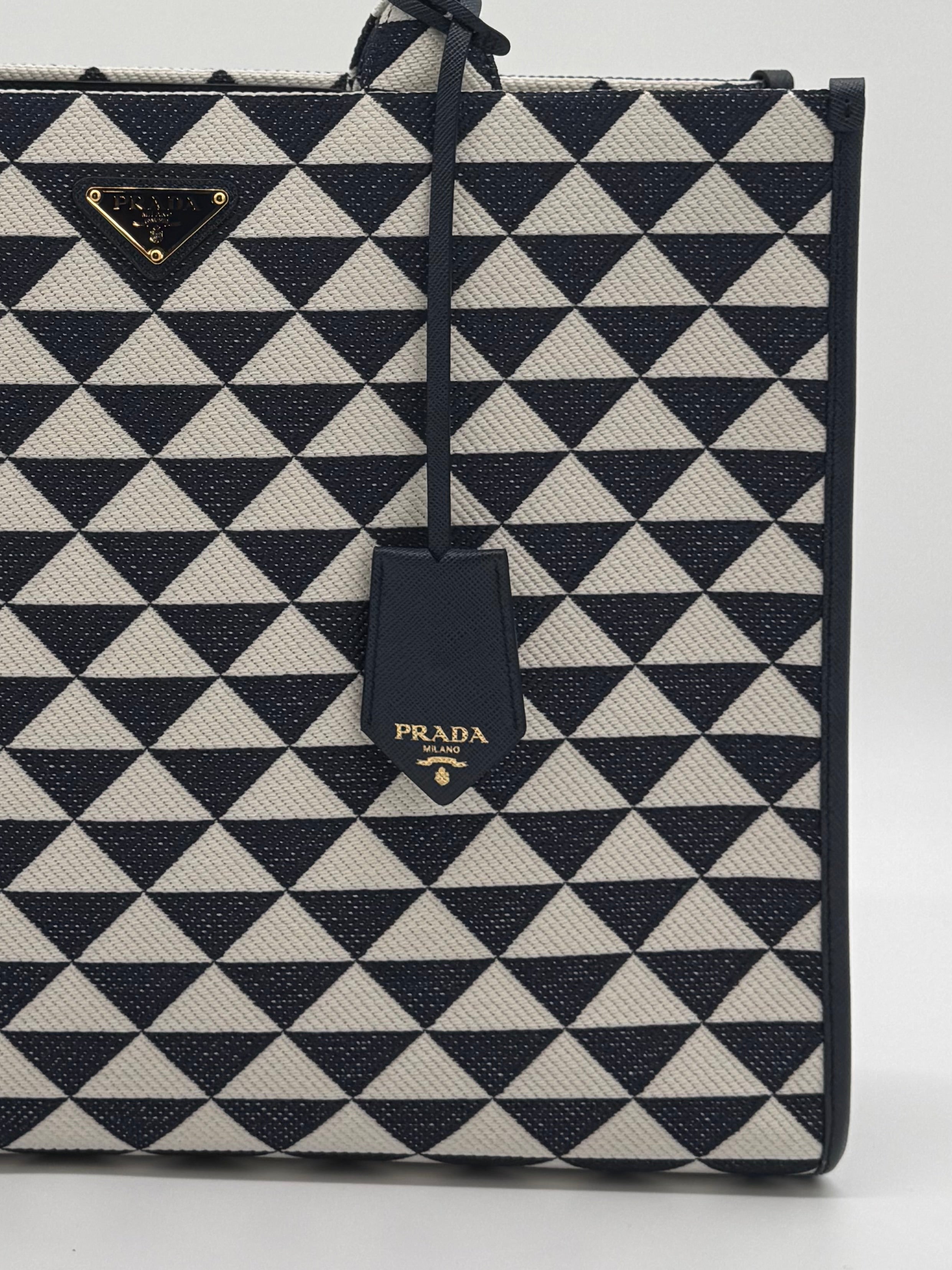 Nahaufnahme des Prada Logos und des Lederanhängers auf dem Jacquard-Stoff.
