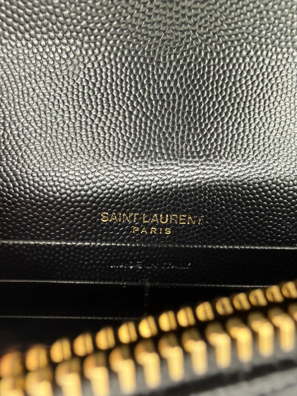Detailaufnahme des goldgeprägten Saint Laurent Paris Logos im Inneren.