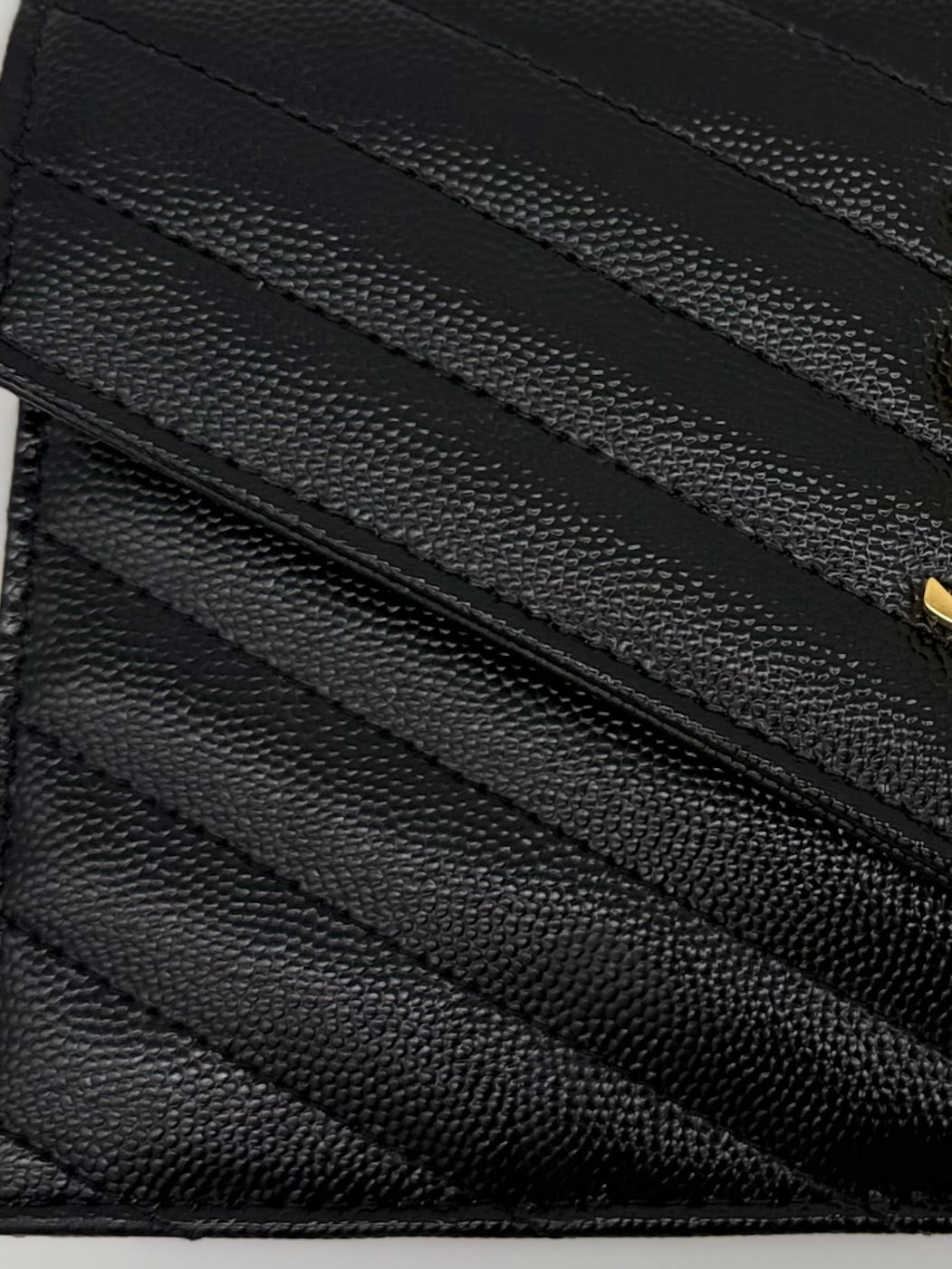 Extremes Close-up der Matelassé-Steppung auf schwarzem Leder.