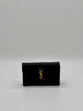 Vorderansicht der Saint Laurent Envelope Cassandre Wallet on Chaîn in Schwarz mit goldenem YSL-Logo.