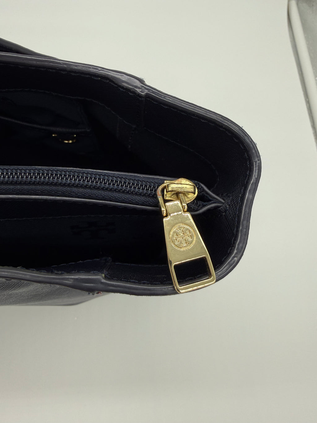 Detail des goldenen Reißverschluss-Zugelements mit Tory Burch Logo